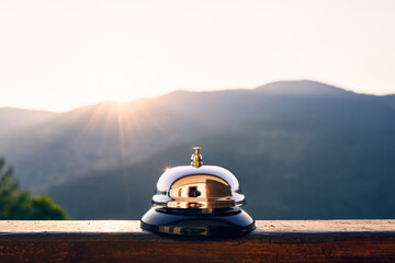 Naklejka na ściany i meble Silver vintage bell on village reception desk in the morning sunrise mountain. Eco, camping hotel service, registration.