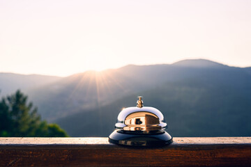 Naklejka na ściany i meble Silver vintage bell on village reception desk in the morning sunrise mountain. Eco, camping hotel service, registration.