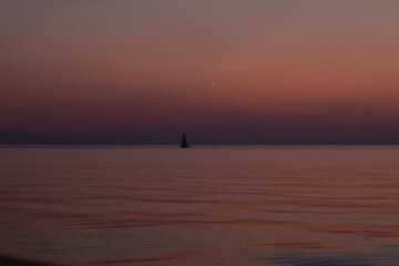 Fototapeta premium Purple sunset and moonrise at the open sea
