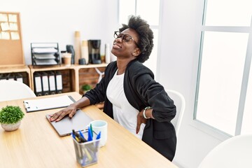 Young african american woman working with backache at office