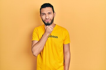 Hispanic man with beard wearing t shirt with happiness word message touching painful neck, sore...