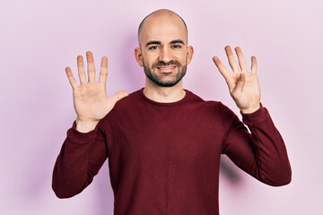 Young bald man wearing casual clothes showing and pointing up with fingers number nine while...