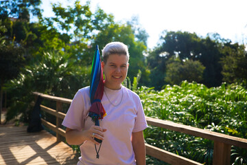 Fototapeta premium non-binary gender non-binary androgynous person with a gay pride umbrella. He is smiling and looking at the camera. Non-binary and androgynous concept. Diversity concept.