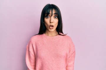 Fototapeta premium Young brunette woman with bangs wearing casual winter sweater afraid and shocked with surprise expression, fear and excited face.