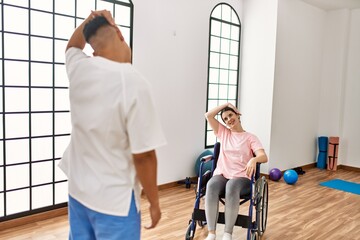 Young disabled woman having mobility exercise sitting on wheelchair at the clinic.