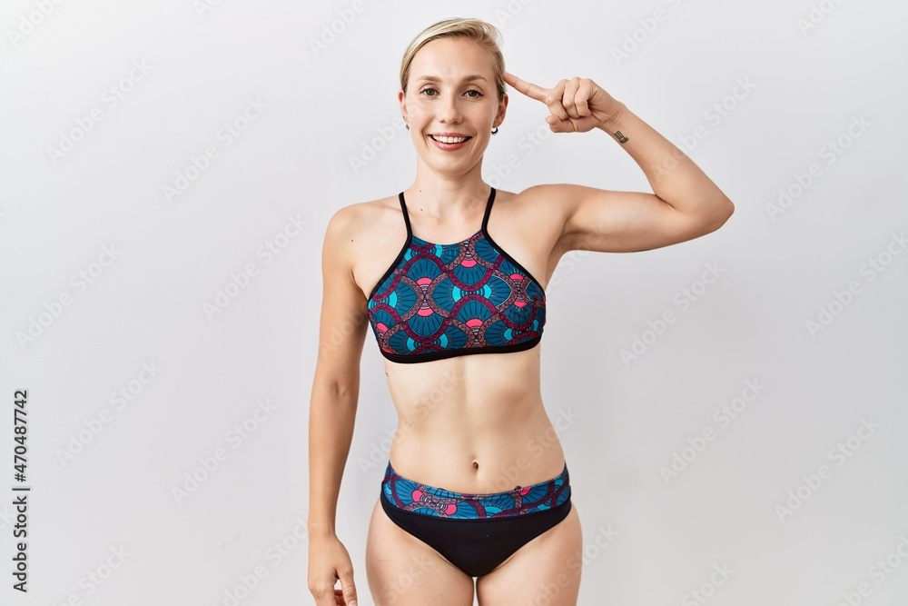 Sticker Young blonde woman wearing sporty bikini over isolated background smiling pointing to head with one finger, great idea or thought, good memory