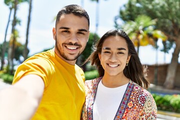 Obraz premium Young latin couple smiling happy and hugging making selfie by the camera at the city.