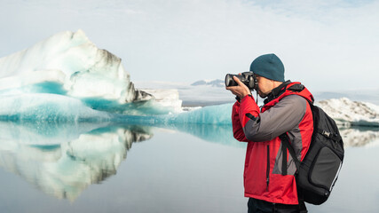 Traveling in Iceland, photographer with DSLR camera in glacier lagoon - obrazy, fototapety, plakaty