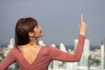 asian woman pointing up in urban environment