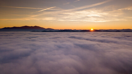 Italy November 2021: aerial view of mountains with fog below in autumn season at sunset