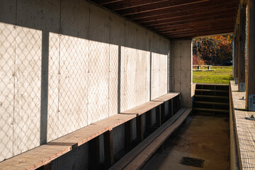 Fototapeta na wymiar Baseball dugout inside with full of sun light. Empty youth sports park in a small rural town in America.