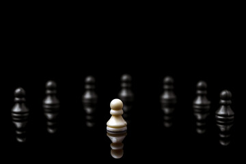 A white chess pawn piece stands on a dark background surrounded by black pieces.