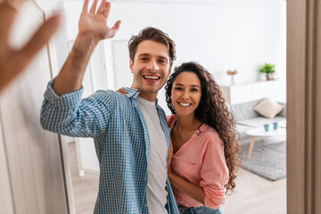 Happy couple inviting people to enter home, giving high five