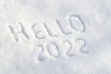 Snow surface and text Hello 2022. Inscription draw on white snow. Happy new year 2022 concept. Top view, above.