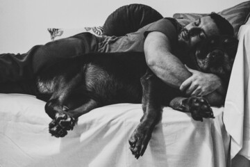 Hombre durmiendo con su perro rottweiler