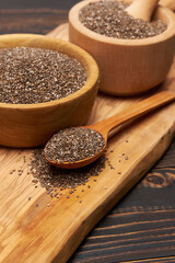 Bowl of organic natural chia seeds close-up on wooden background or table