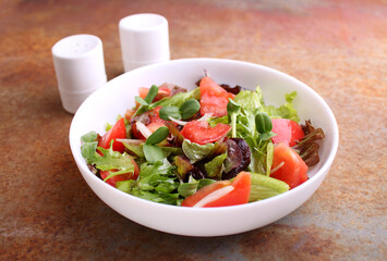 Healthy salad in a white plate of greens, tomatos and microgreen on a old background.