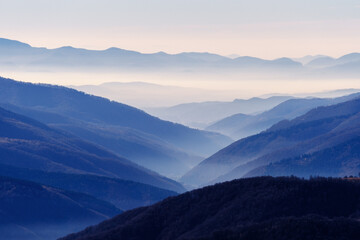 mountain ranges and slopes covered with forest in fog
