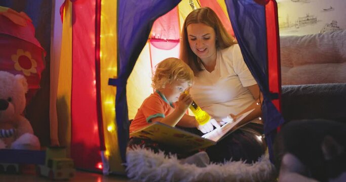Happy loving family. Young mother and her son boy play in children room at the bedtime. Mom and lovely child are having fun with flashlights indoors. Family concept