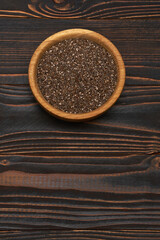Bowl of organic natural chia seeds close-up on wooden background or table
