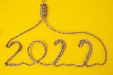 2022 written with jute rope, forming a hangman noose on a yellow backgroud