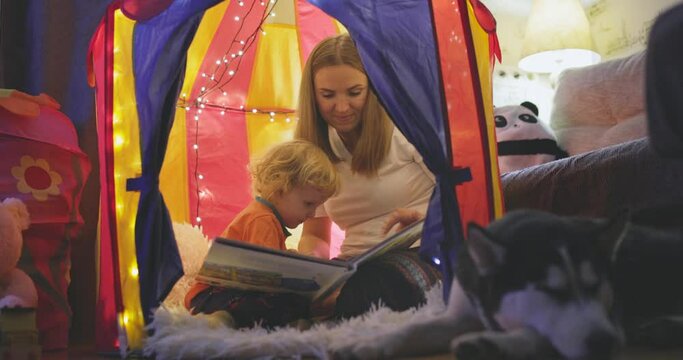 Happy loving family. Young mother and her son boy play in children room at the bedtime. Mom and lovely child are having fun with flashlights indoors. Family concept