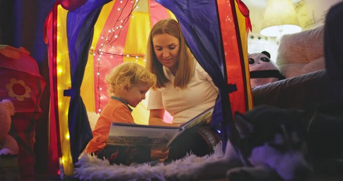 Happy loving family. Young mother and her son boy play in children room at the bedtime. Mom and lovely child are having fun with flashlights indoors. Family concept
