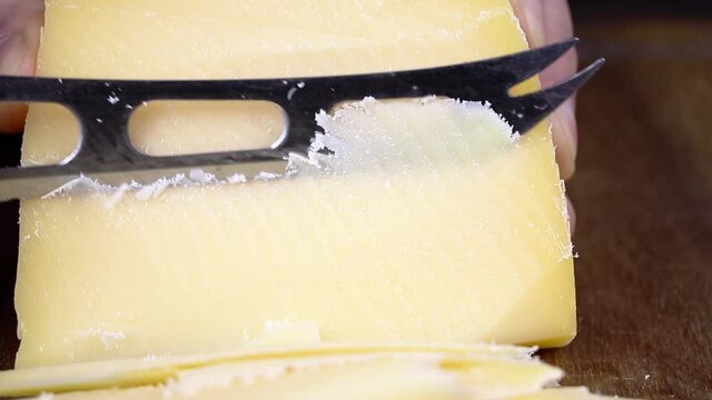Slicing cheese. A man cuts cheese on a cutting board.Hard cheese varieties. Parmesan cheese.