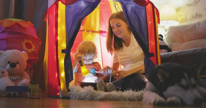 Happy loving family. Young mother and her son boy play in children room at the bedtime. Mom and lovely child are having fun with flashlights indoors. Family concept