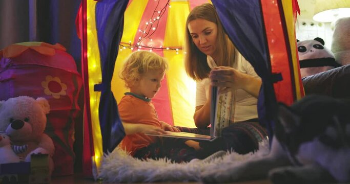 Happy loving family. Young mother and her son boy play in children room at the bedtime. Mom and lovely child are having fun with flashlights indoors. Family concept