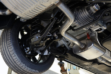 A modern car in a car service on a lift. Bottom view of the car. Details and structure of the...