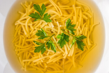 Traditional broth with noodles and parsley, close-up
