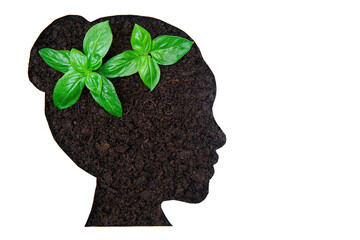 Woman's head profile made of soil with two young plants