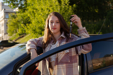 A girl with a car key in her hand. Rent, sale and purchase of a car