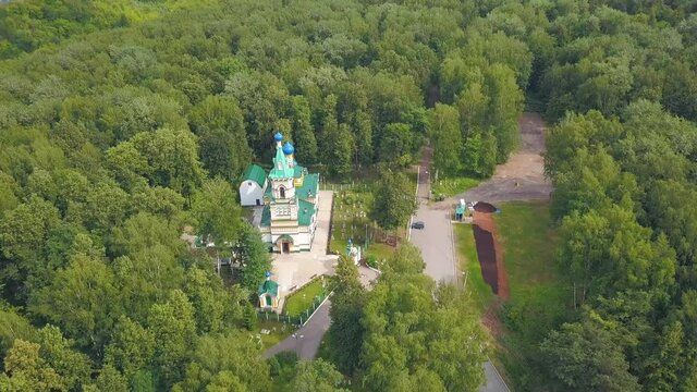 Bird's-eye view. Clip. A beautiful green forest with a monastery in the middle . There are also some roads and some places of the city in the background.