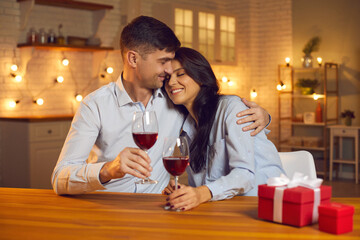 Happy loving couple hugging, deinking wine, giving holiday presents and celebrating Valentines day at home together. Love, Valentines day, togetherness, birthday, dating, couple concept