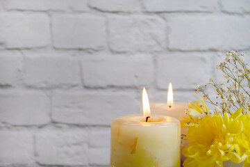 Obraz na płótnie Canvas burning candle color chrysanthemum on a brick background