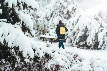 Girl backpacker walking on a forest road in the winter forest. Blurred background