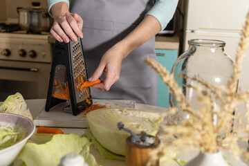 Sauerkraut canning. A young woman prepares homemade sauerkraut with carrots in the kitchen. Fermented food.