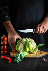 Chef cutting cauliflower in a restaurant kitchen. The idea of a delicious diet for breakfast or dinner