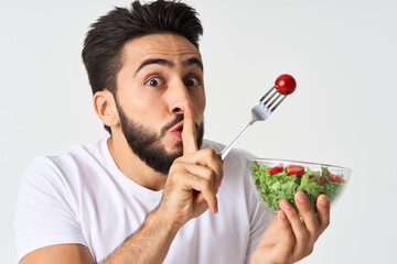 cheerful man in a white t-shirt a plate with salad vegetables diet
