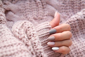Women's hands with a beautiful matte oval manicure in a warm knitted sweater. Winter trend, polish...