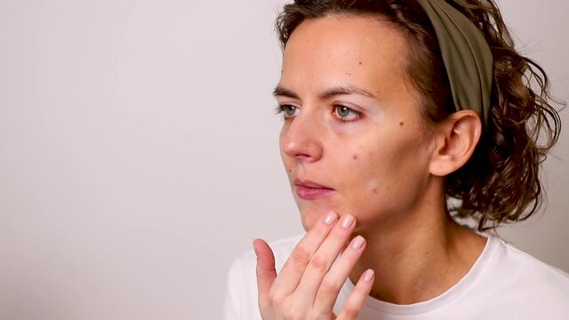 A girl with the autoimmune disease vitiligo paints over the spots with foundation.