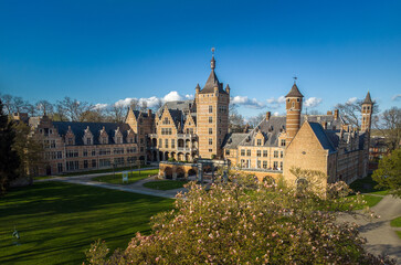 Obraz premium Castle Cantecroy in Mortsel Antwerp behind a treetop and blue sky in the background. Drone aerial view photo at a beautiful sunny day in spring