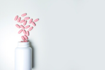 Pink pills in a white jar. Tablets on a white background