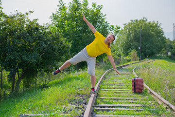 a gloomy traveler with a suitcase on the rails goes