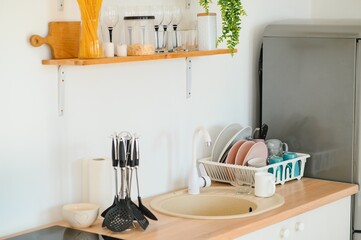 Kitchen brass utensils, chef accessories. Hanging copper kitchen with white tiles wall