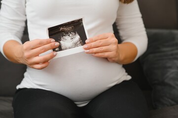 Pregnant woman hands holding ultrasound photo