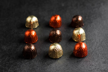 Chocolate candies wrapped in colorful foil on dark background