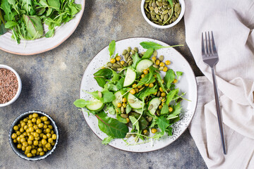 Fresh green salad with cucumber, peas and arugula, mizuna and chard leaves on a plate on the table. Vitamin and healthy food. Vegetarian and Flexetarian Diet. Top view